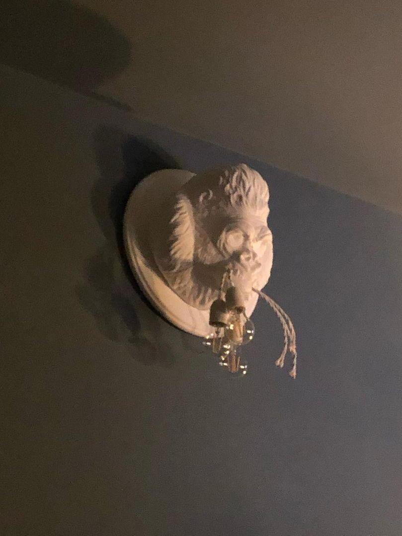 White gorilla relief high on wall in dim room with shadow near ceiling