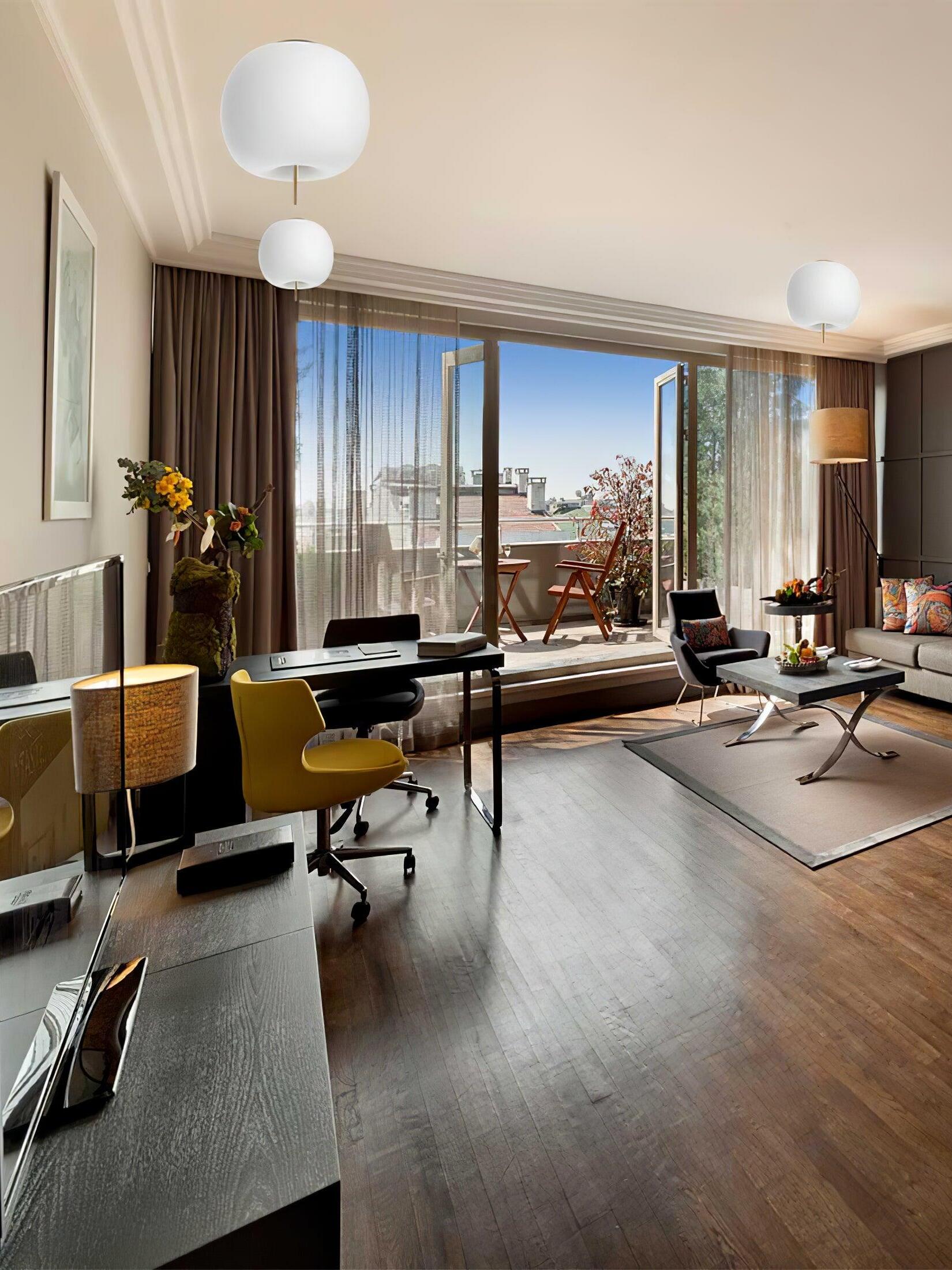 Rounded white ceiling fixtures in a windowed room with desks, office chairs and a seating area