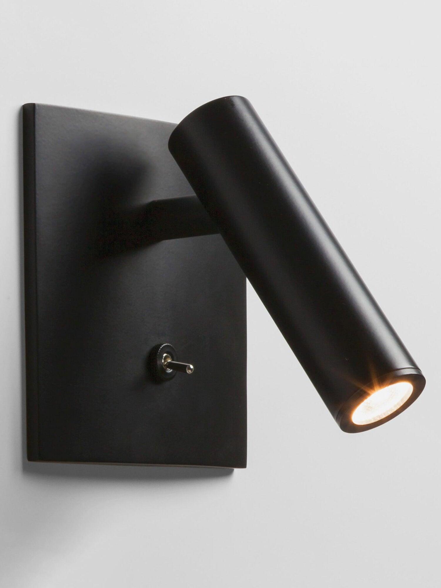 Close black Enna wall light with angled illuminated cylinder, square plate, short arm and lower toggle