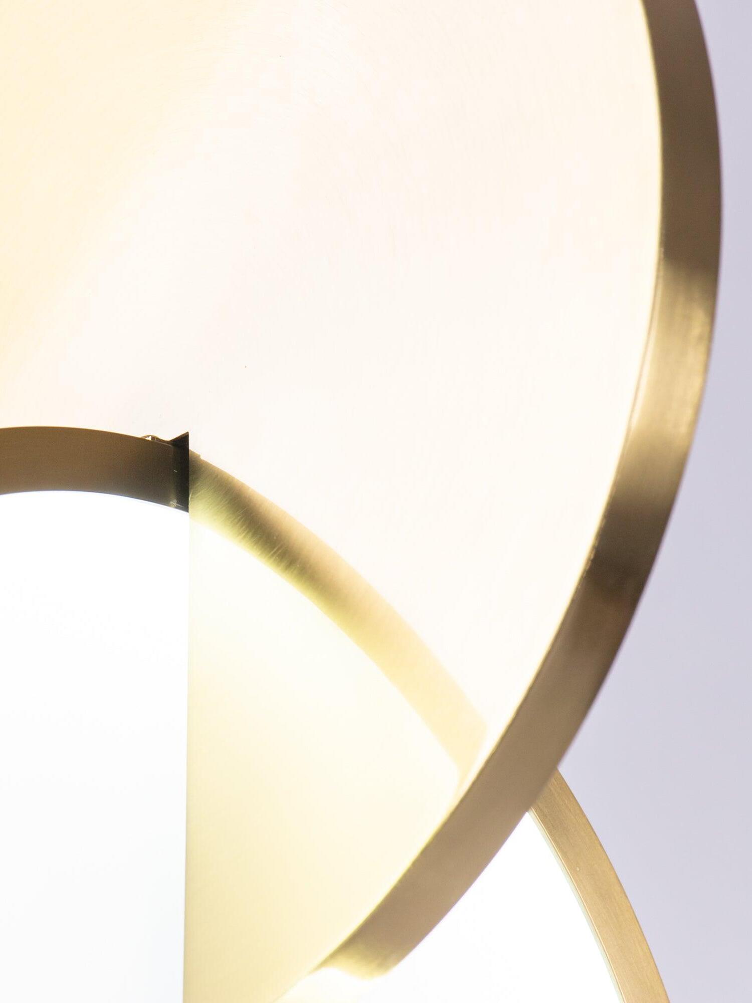 Close detail of the illuminated white diffuser and intersecting gold disc rim