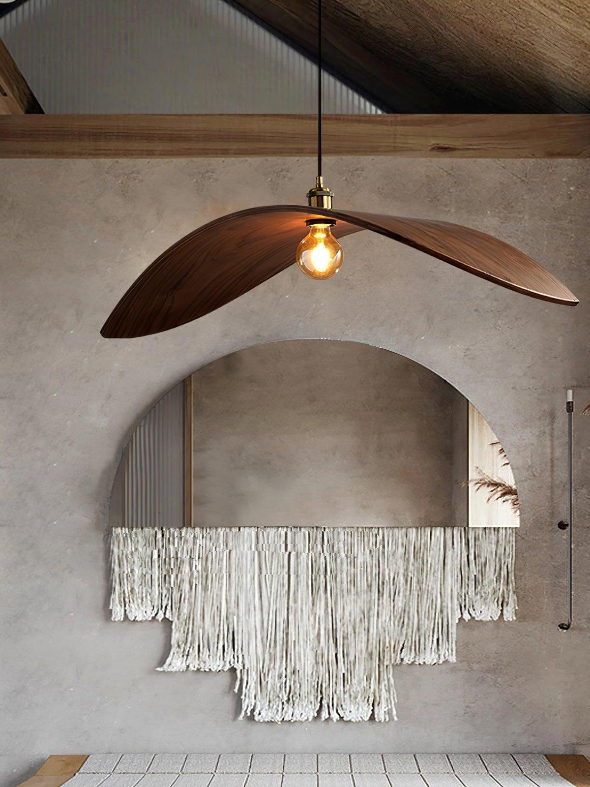 Dark wood-tone curved pendant near an arched mirror against a textured wall