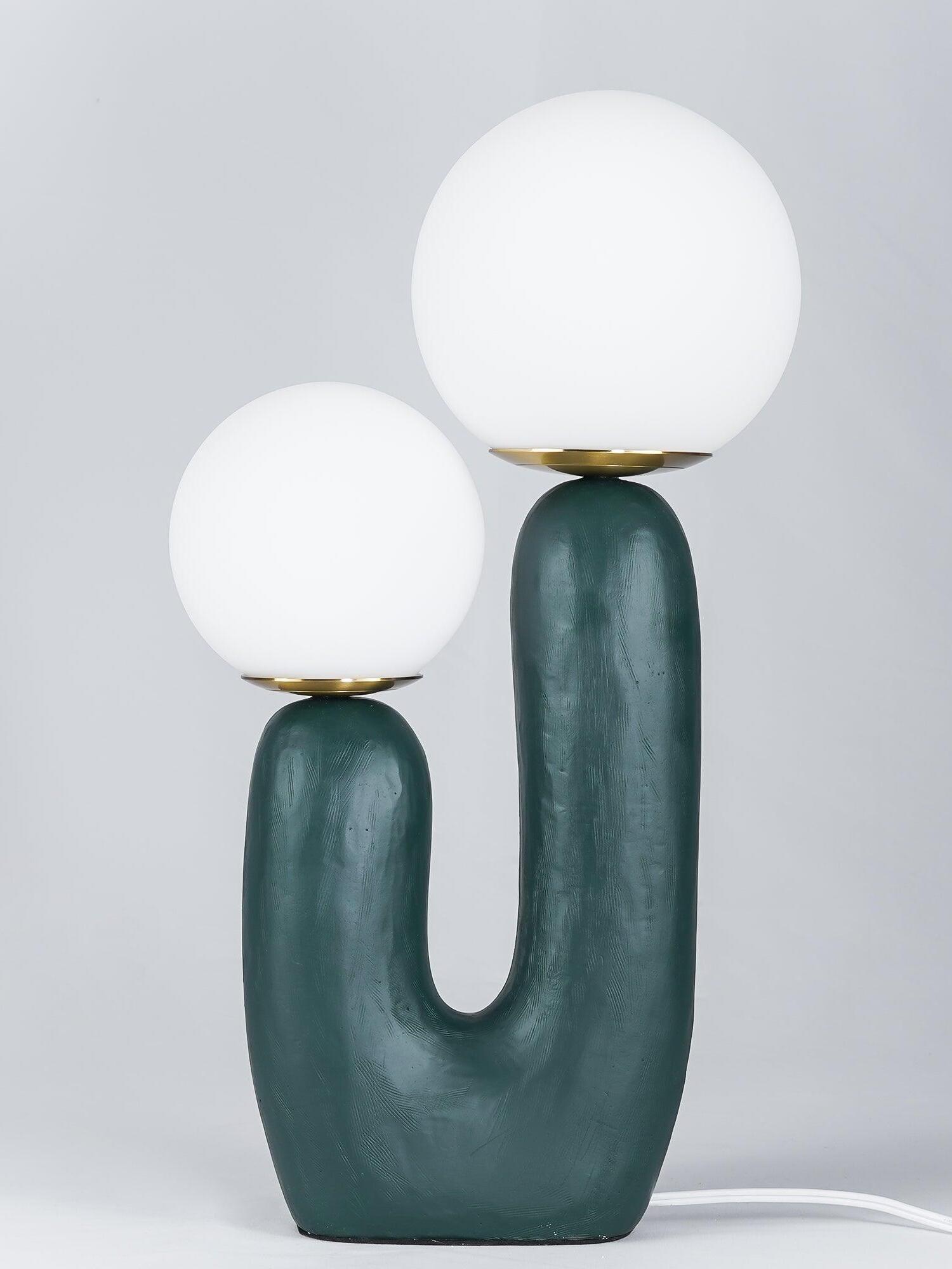 Green Oo Rough lamp against grey with unlit-looking opal globes, textured U-shaped body and white cord