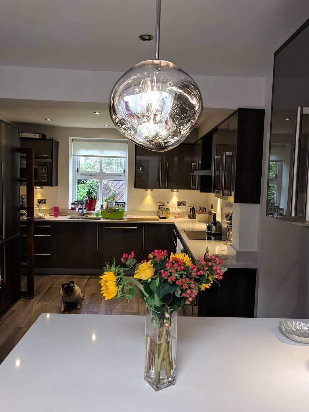 Silver reflective pendant above a kitchen island