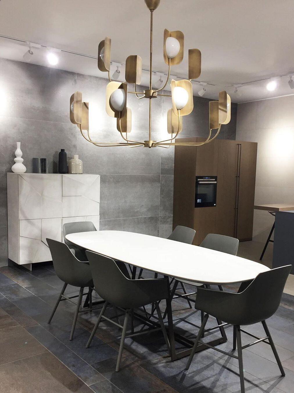Gold-coloured leaf-shield chandelier above a dark dining setting