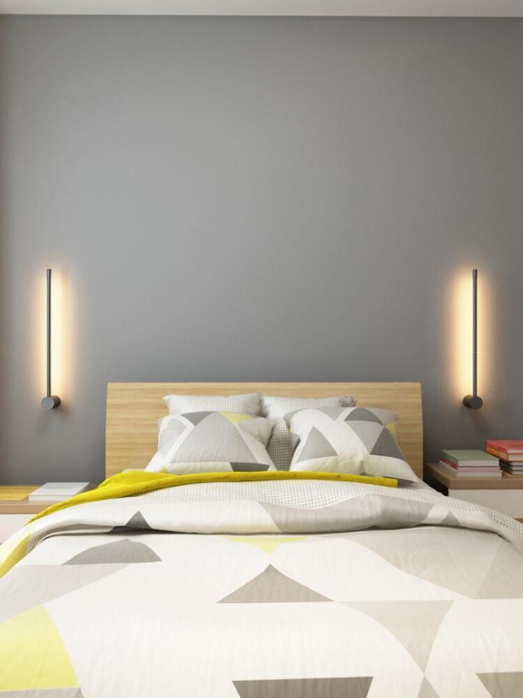 Two slim wall lights beside a bed with yellow bedding