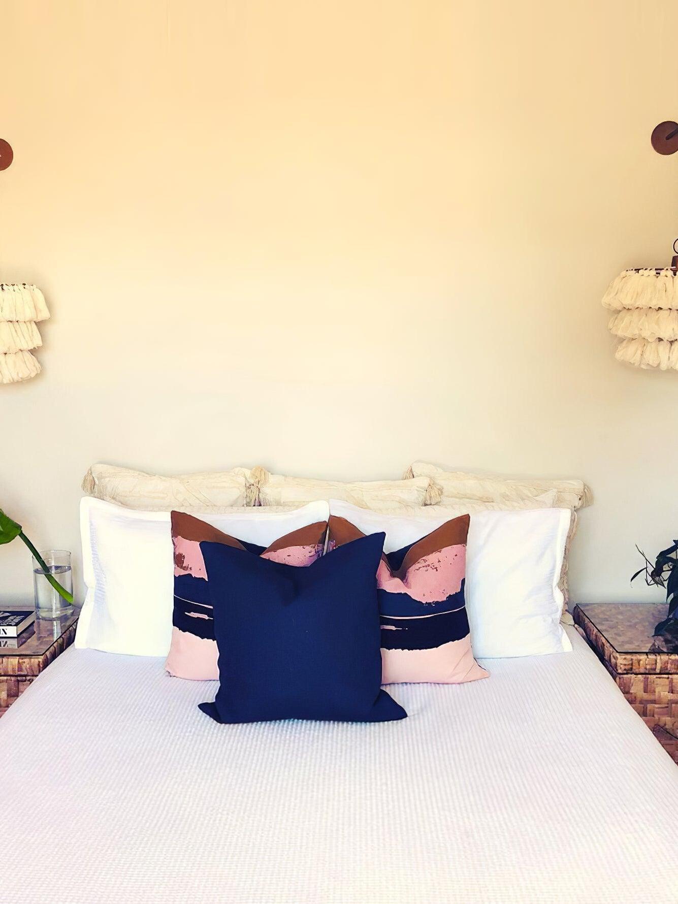 White tassel lights above a bed with dark pillows