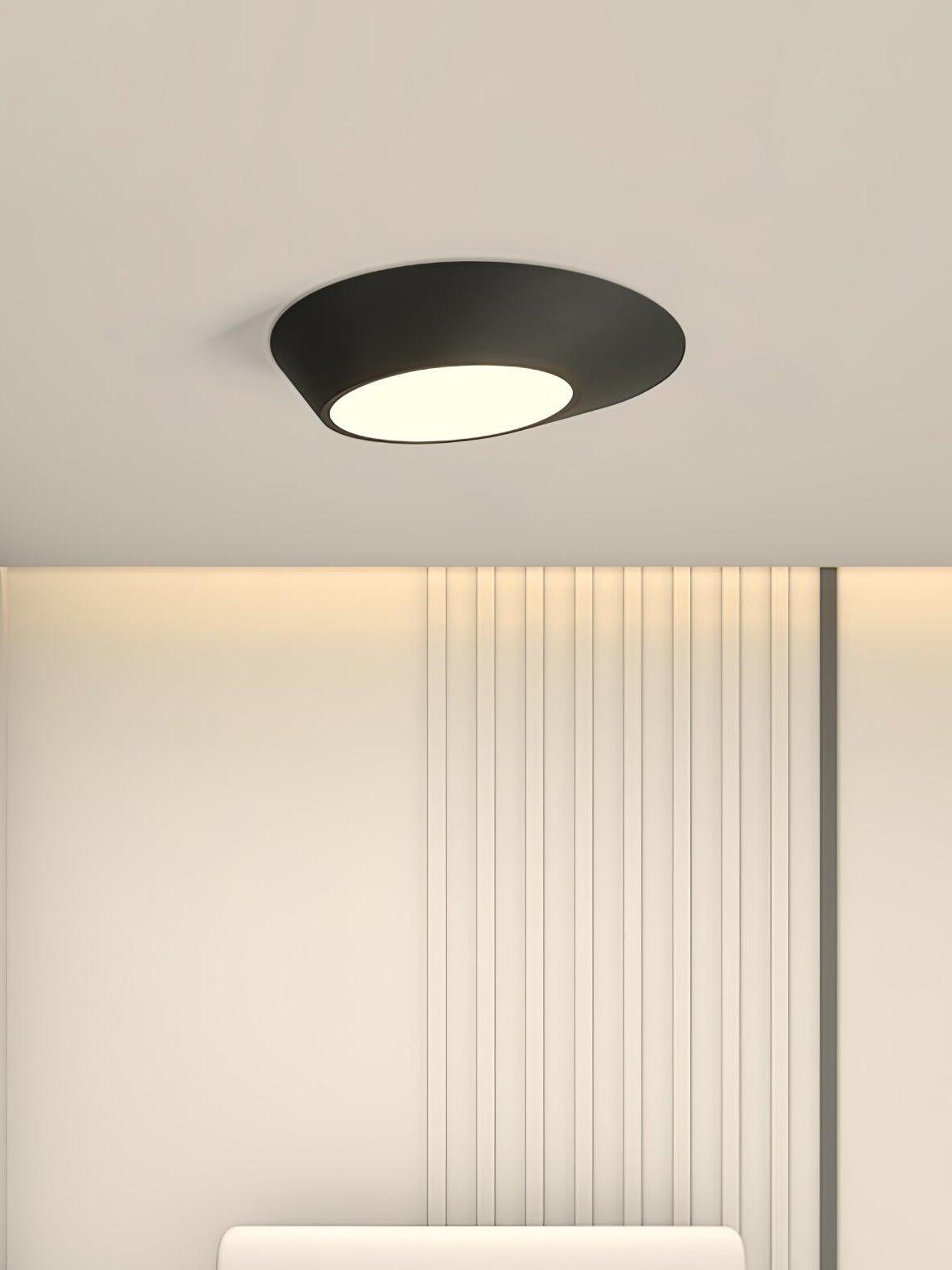 Close view of a black angled ceiling light above a white bedhead and vertical slats