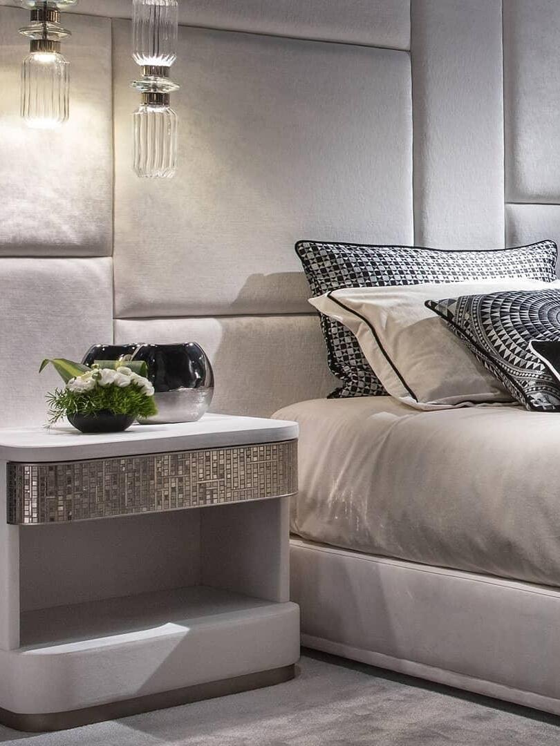 Slim clear glass pendant suspended beside a bed
