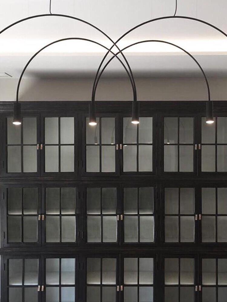 Overlapping arch pendant above a dark cabinet