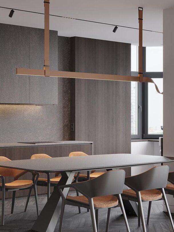 Brown pendant viewed across a long dining table with black chairs and a dark wall behind