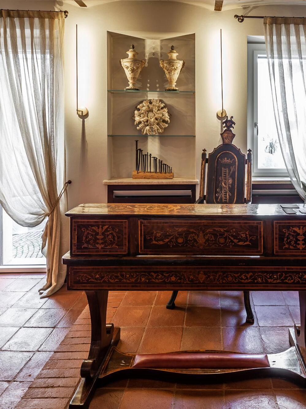 Vertical wall sconce beside an ornate desk