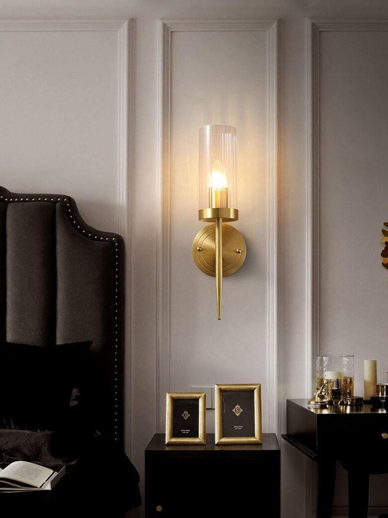 Single sconce above framed pictures by a bed
