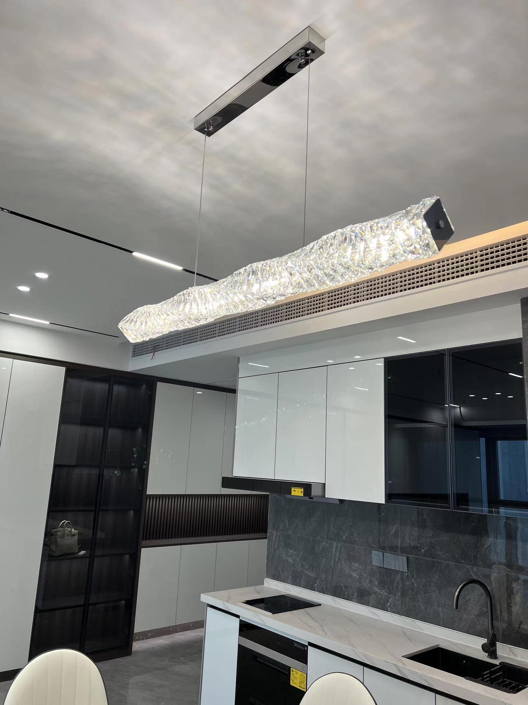 Angled view of the chrome canopy and clear crystal bar above a modern kitchen
