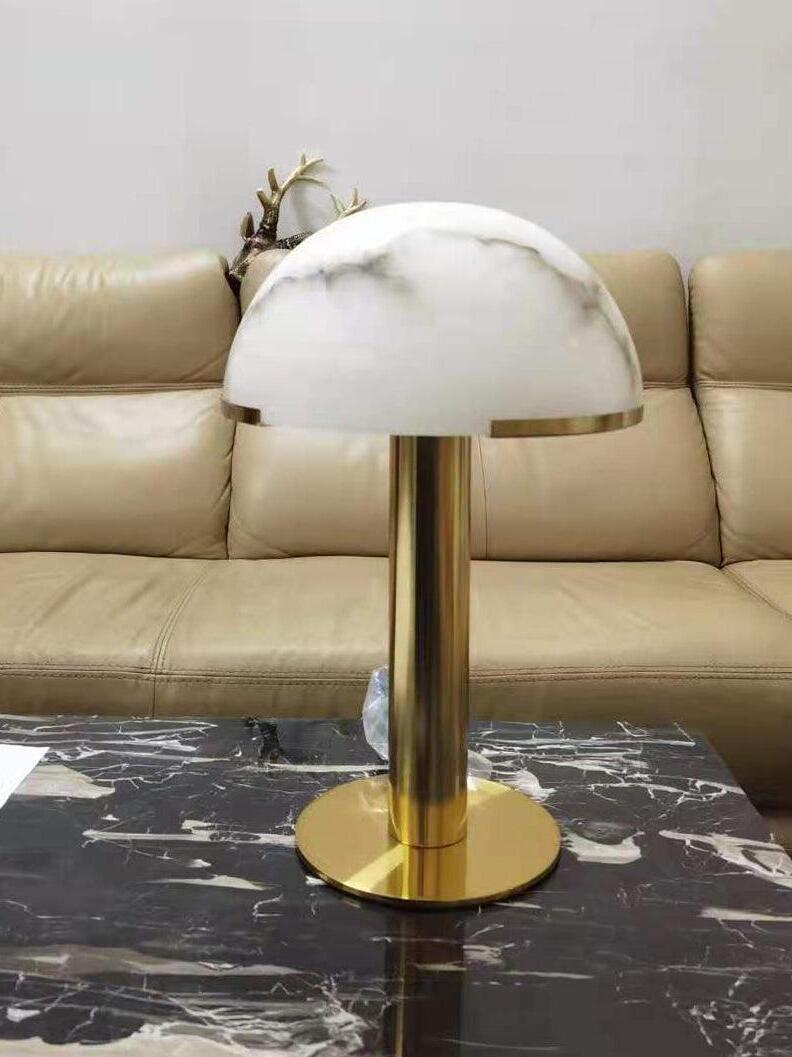 Melange gold-coloured table lamp with brown veining across its pale dome shade