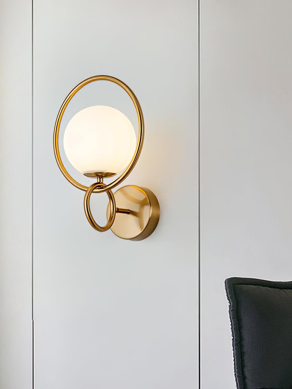 Gold ring and glass globe wall light on paneled wall