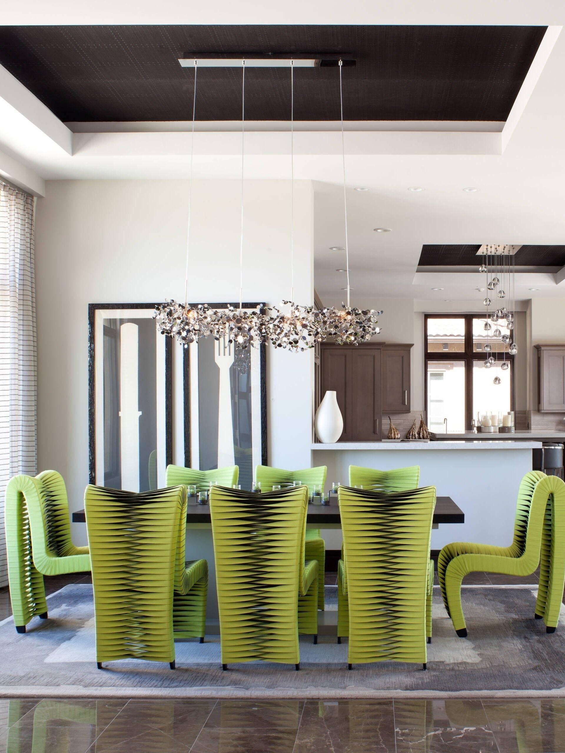 Long silver disc chandelier above a table with green chairs