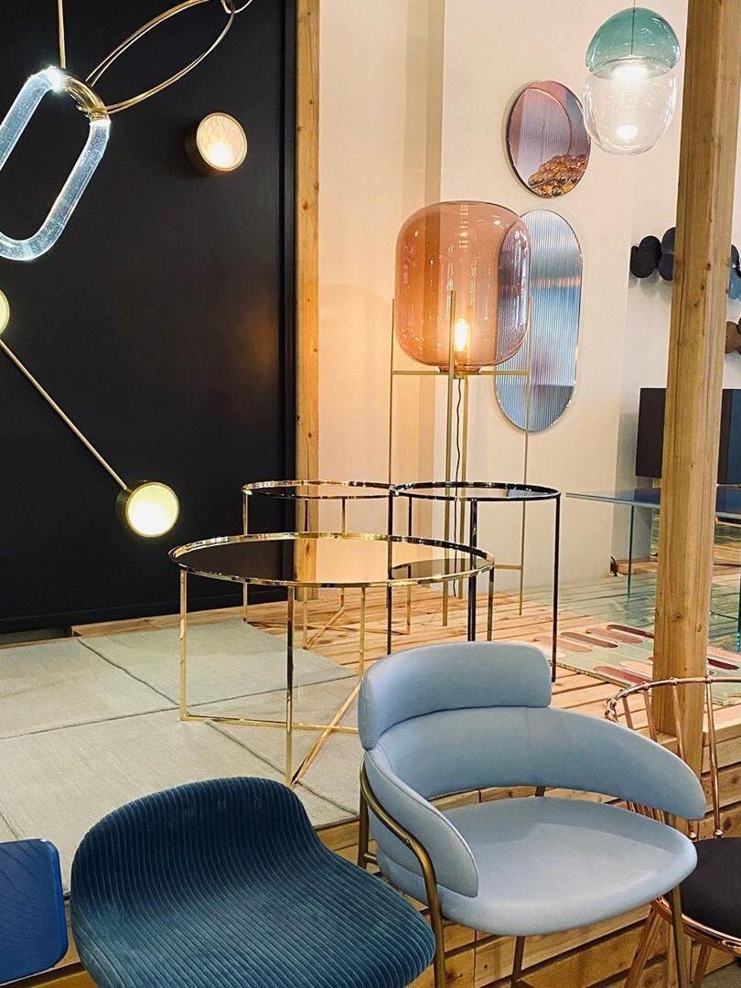 Amber glass floor lamp in a showroom with blue chairs and decorative mirrors.
