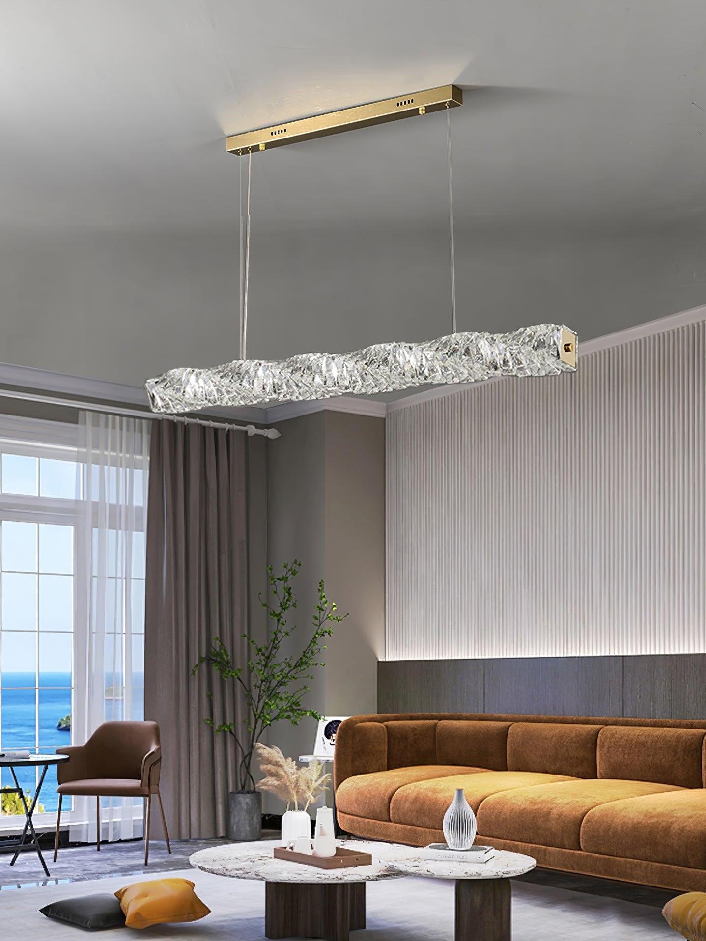 Gold canopy and cool-looking crystal pendant above a brown sofa and pale wall panelling