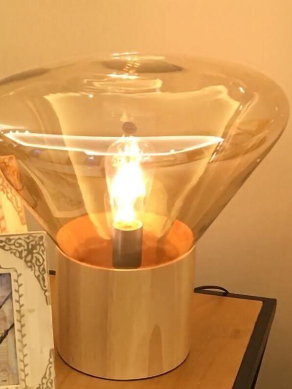 Close amber glass shade surrounding lit bulb above wood base on table