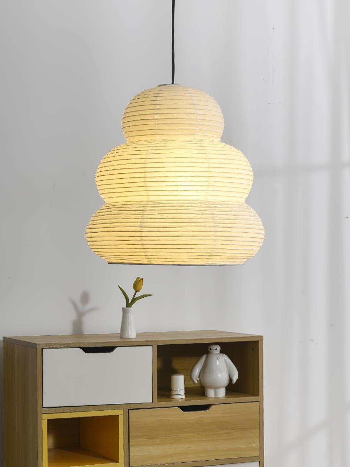 Tiered white paper pendant glowing above a cabinet