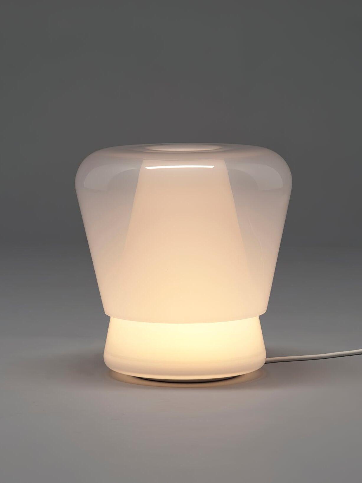 Lit white Jumelle glass lamp on grey background