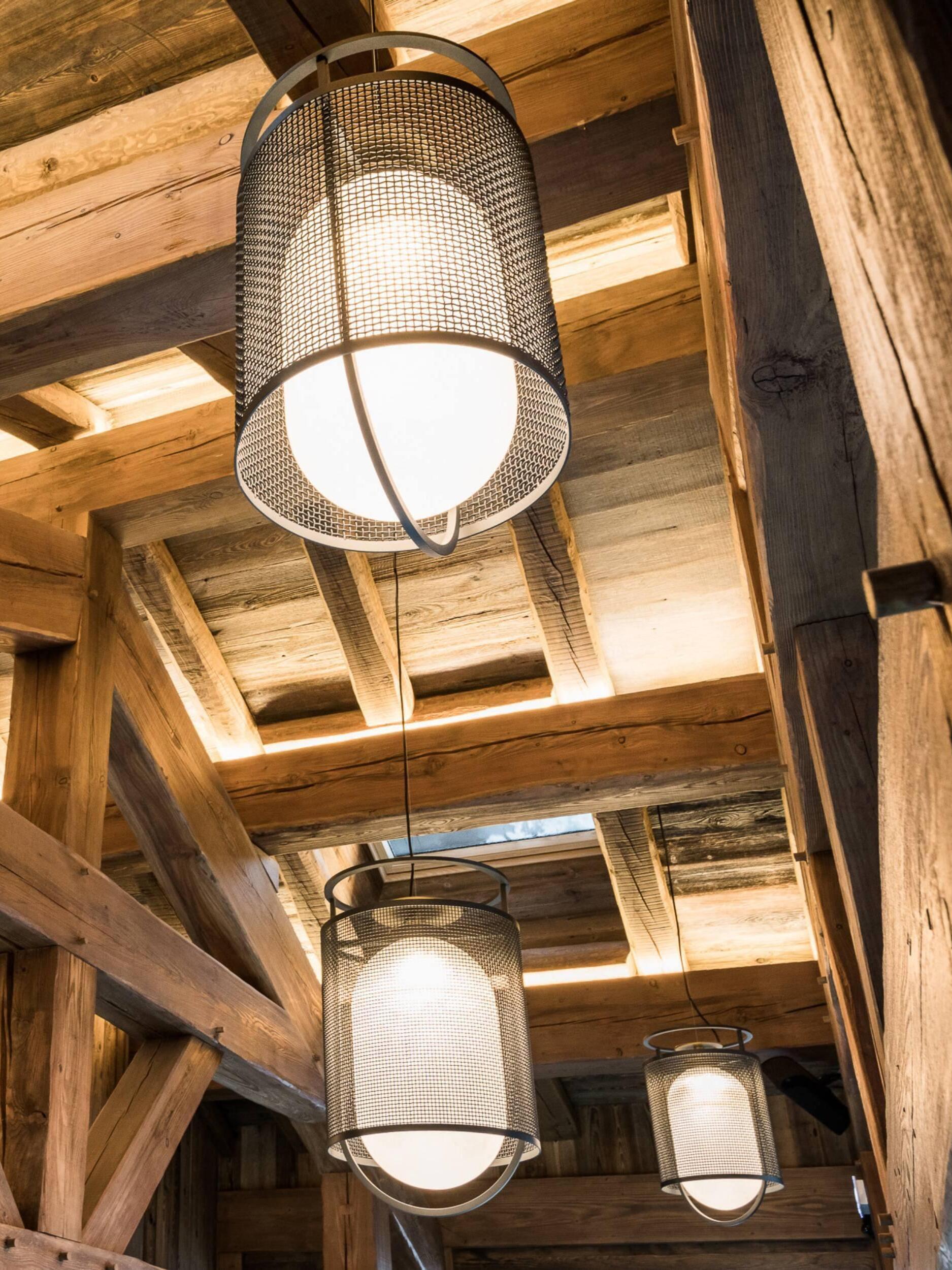 Black mesh lantern beneath timber beams beside a pool
