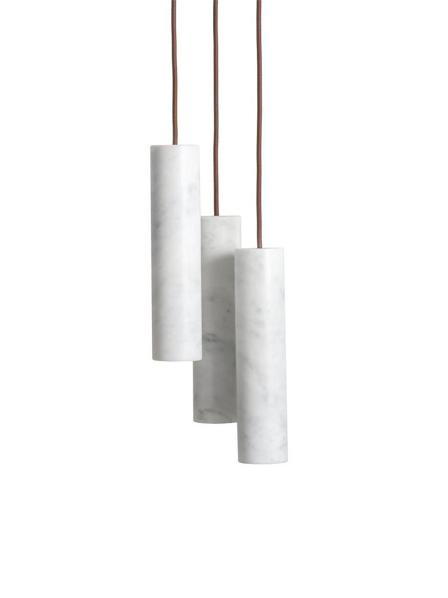 Three white Silo cylinders on brown cords hanging at different heights on a pale background