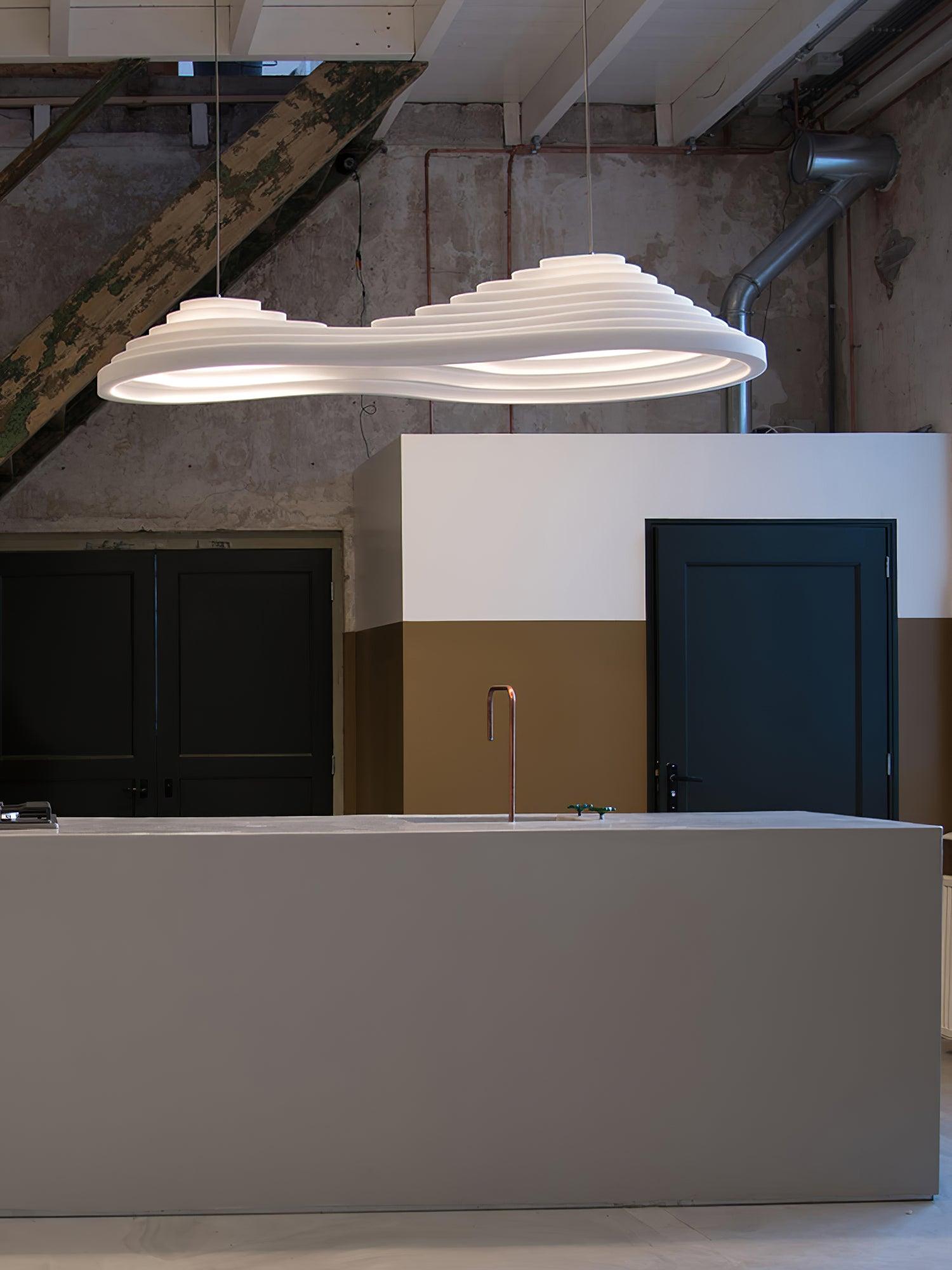 Wide view of an elongated white pendant over a pale counter with dark cabinet panels behind.