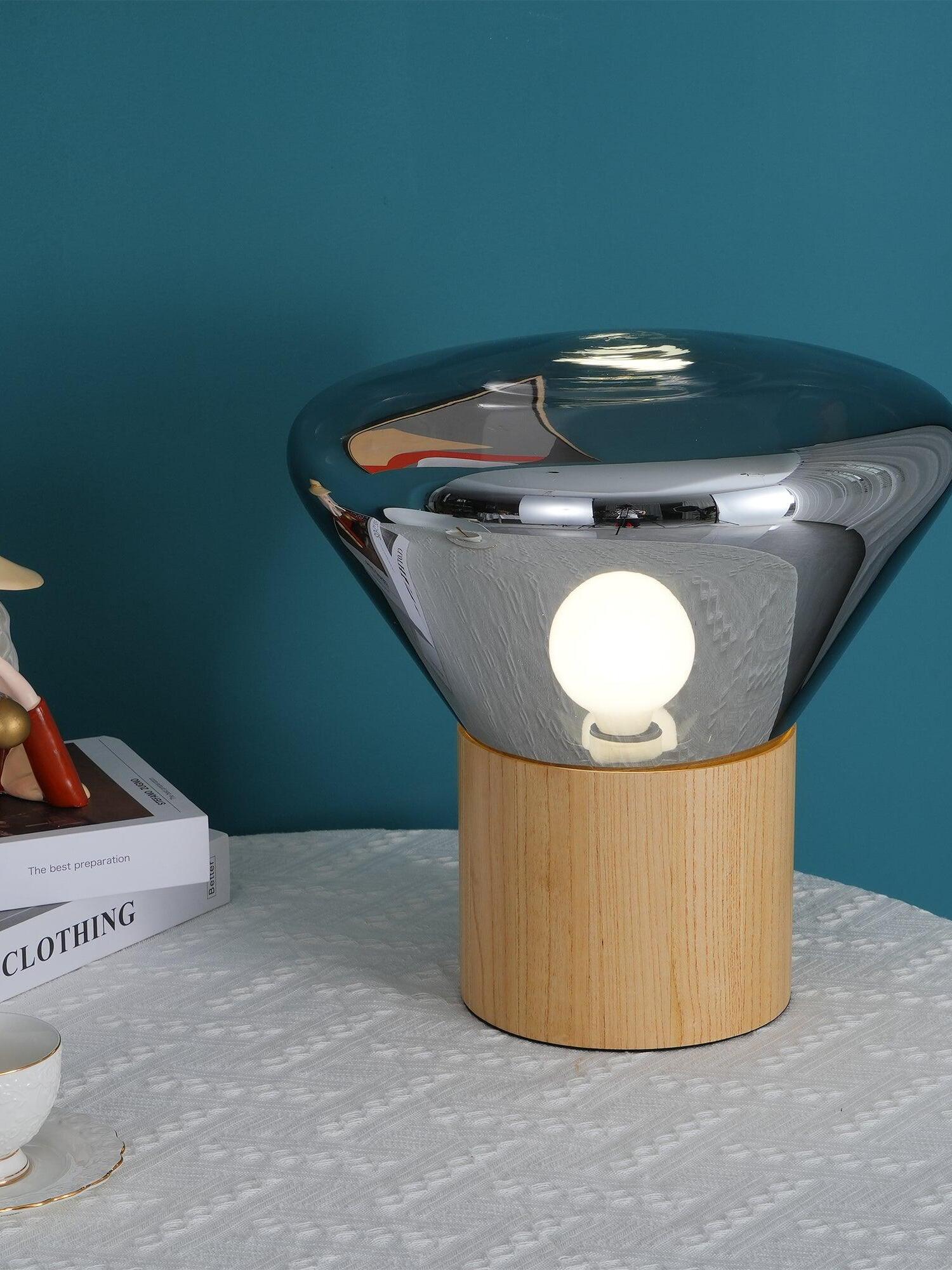 Closer smoky glass lamp with round illuminated bulb on textured tabletop