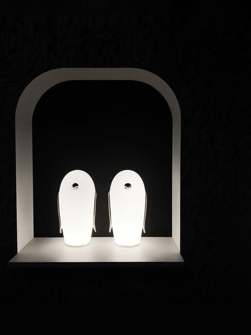 Two tall glowing penguin lamps inside arch against dark background