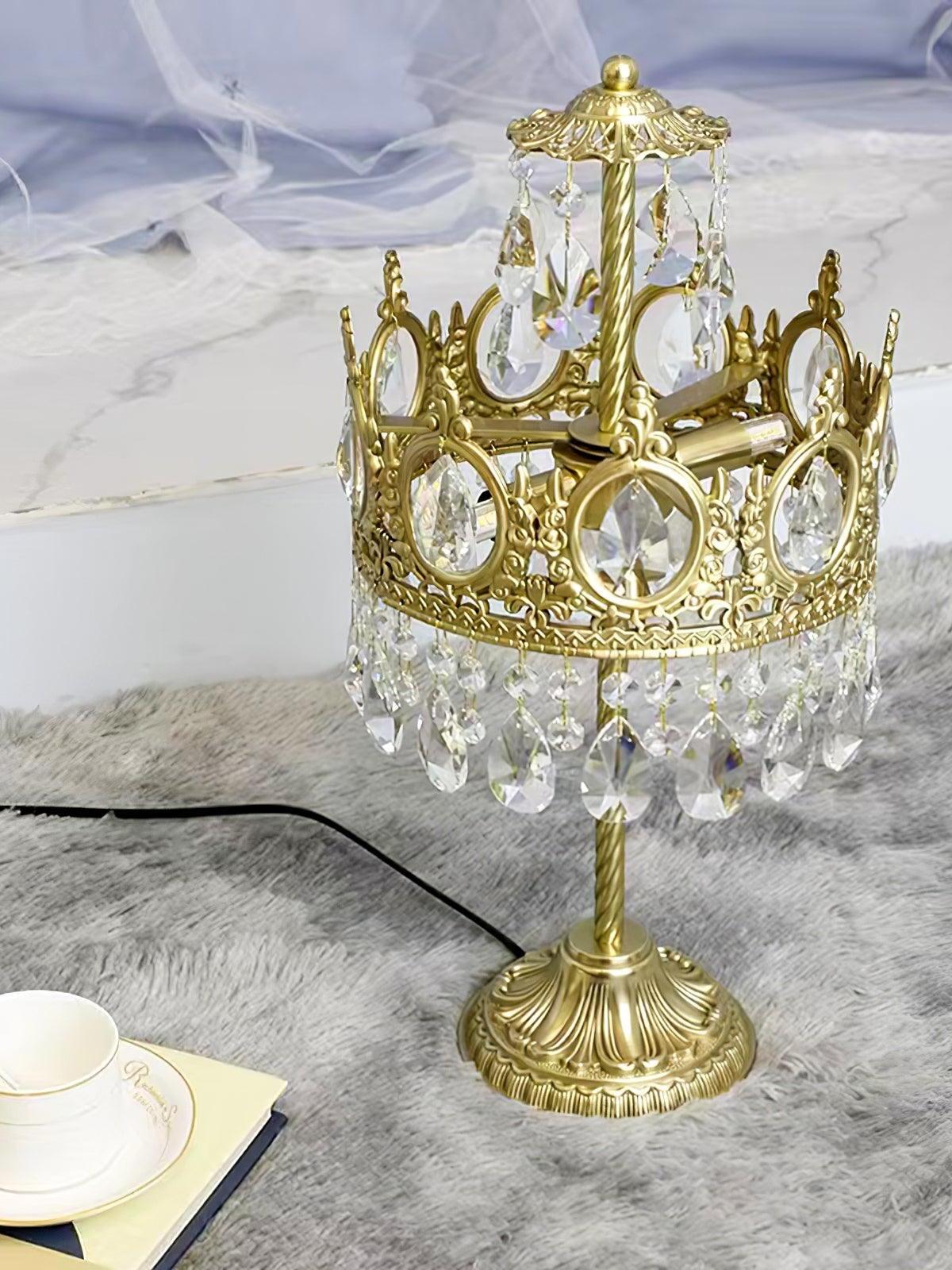 Crystal table lamp on a grey surface beside a cup, with a black power cord trailing from the base.
