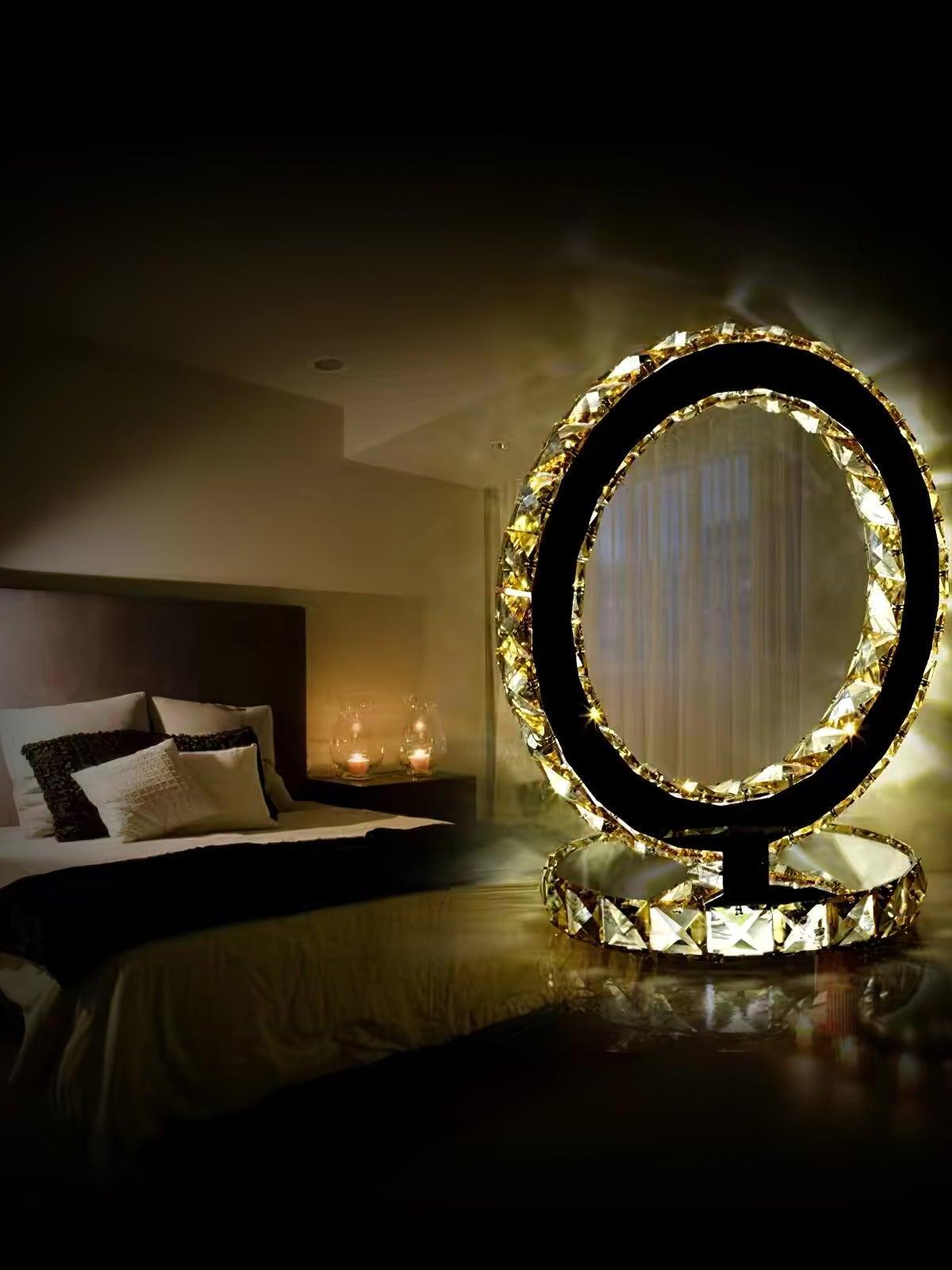 Warm-looking ring lamp on a bedside surface with a bed and curtains behind it
