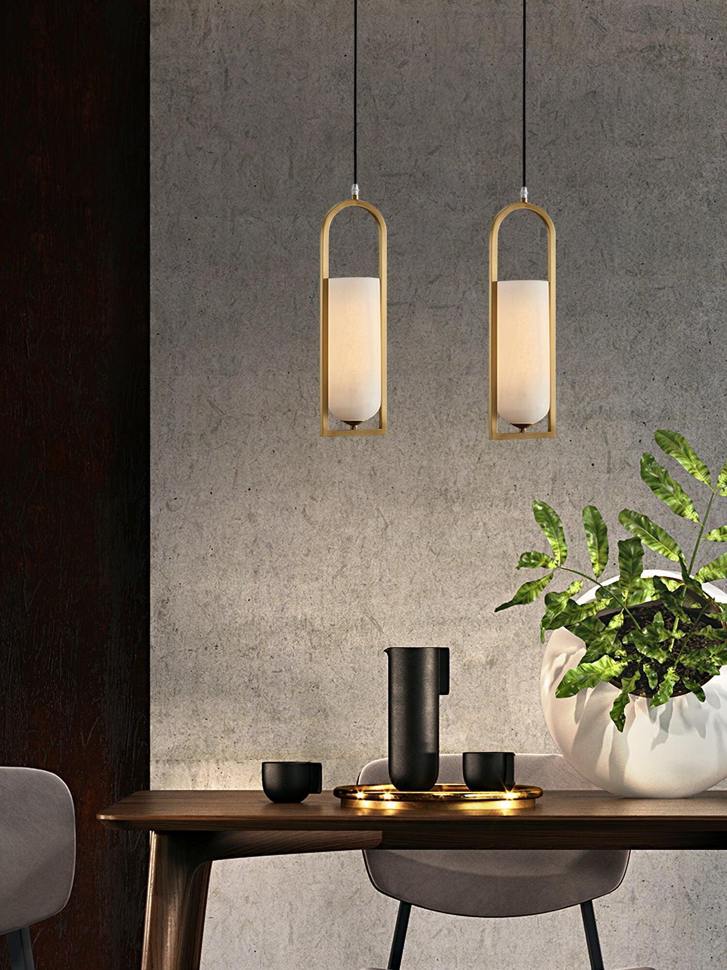 Two glowing Melange pendants above a table with dark cups, a tall vessel and green foliage