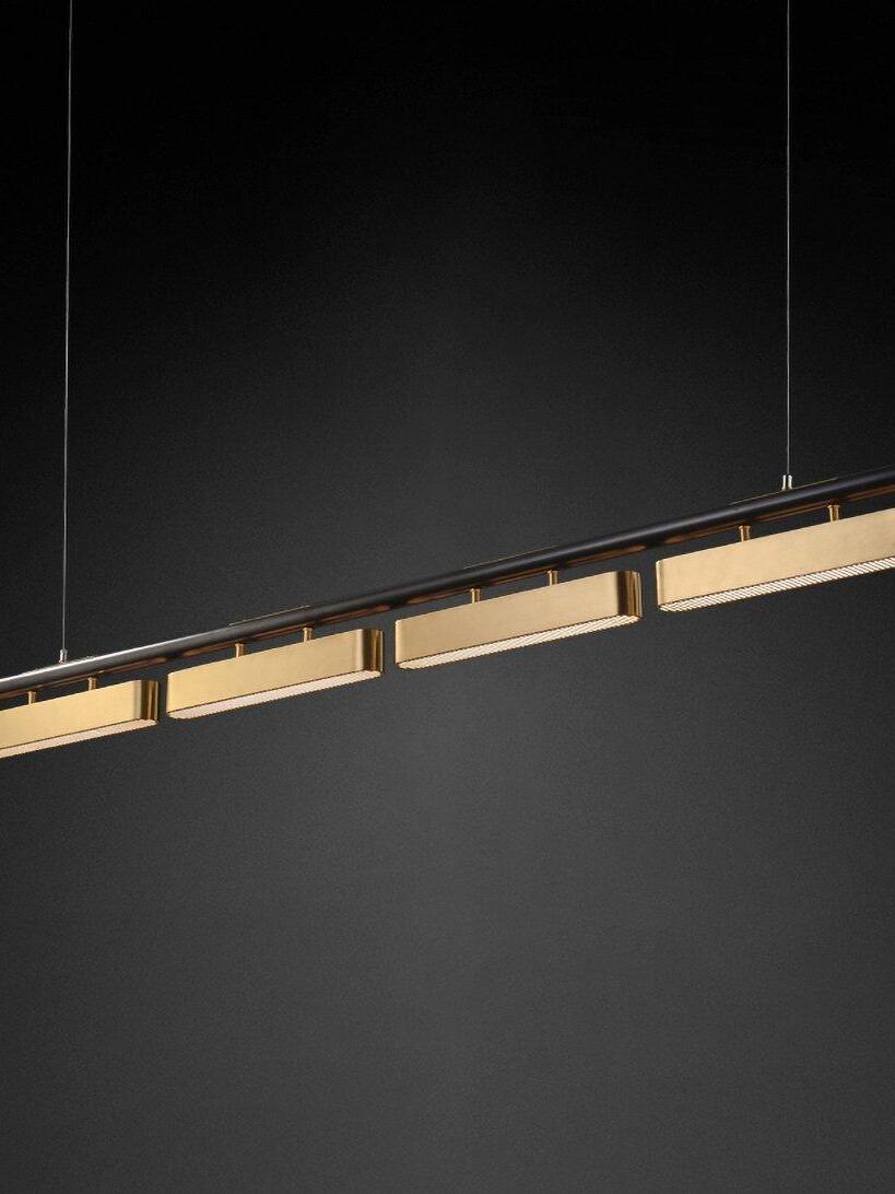 Angled Colt four-module linear fixture on black, showing lit slotted undersides and two suspension wires