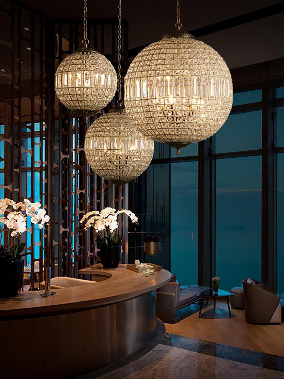 Three glowing crystal globes at staggered heights above a curved counter with orchids beside tall windows