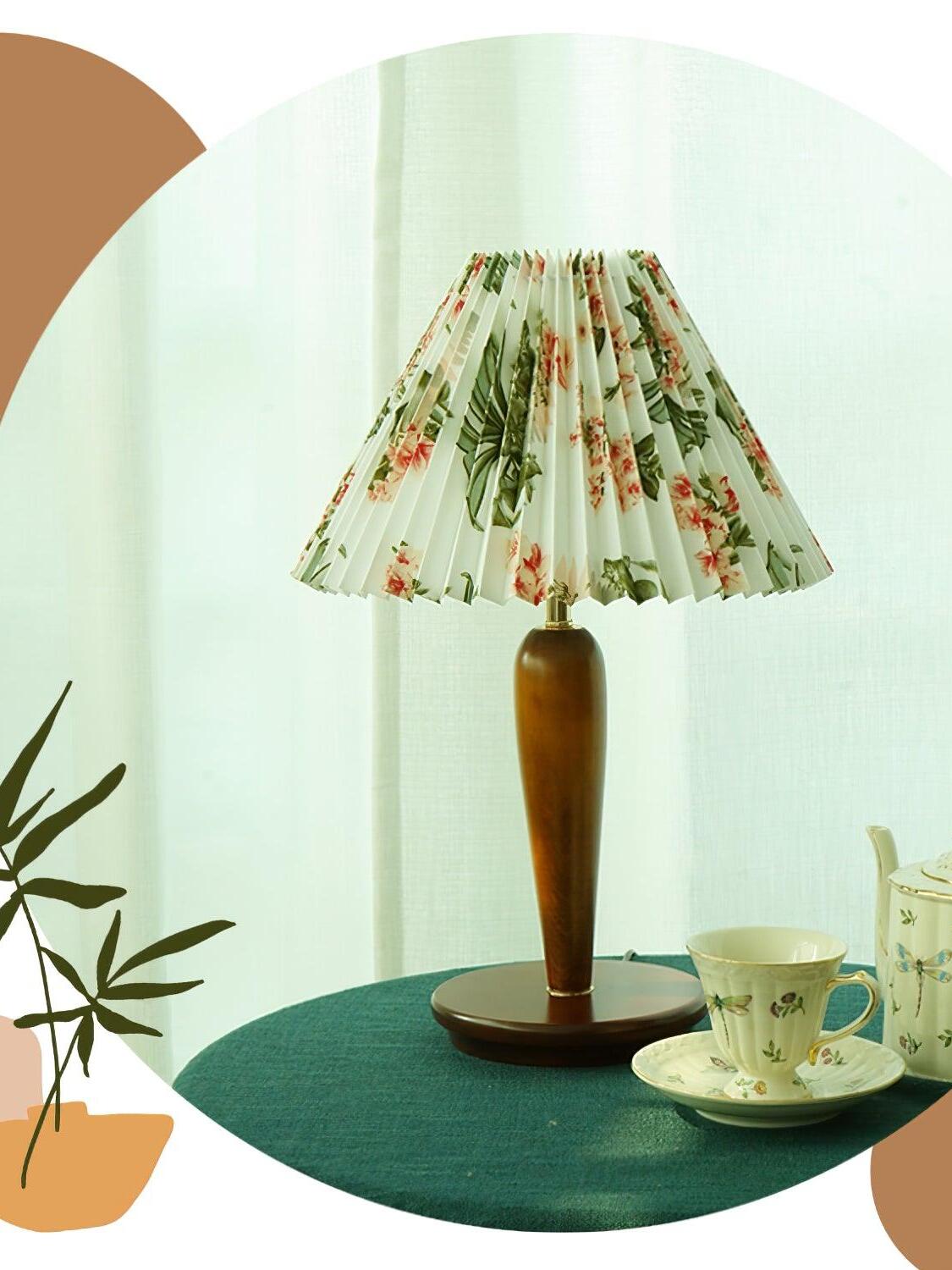 Brown table lamp with floral pleated shade beside teacup