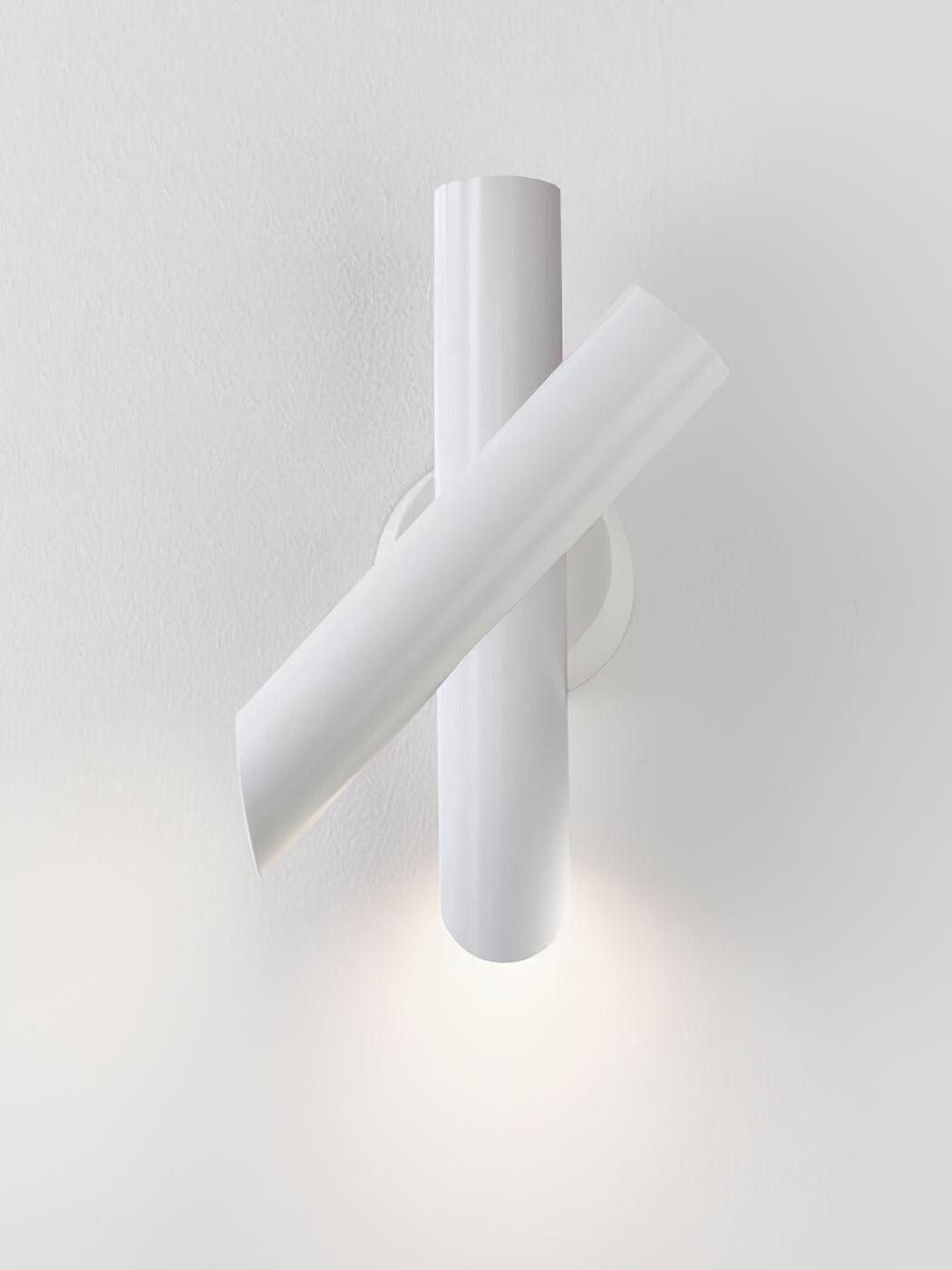 White crossed-tube lamp lighting the wall below
