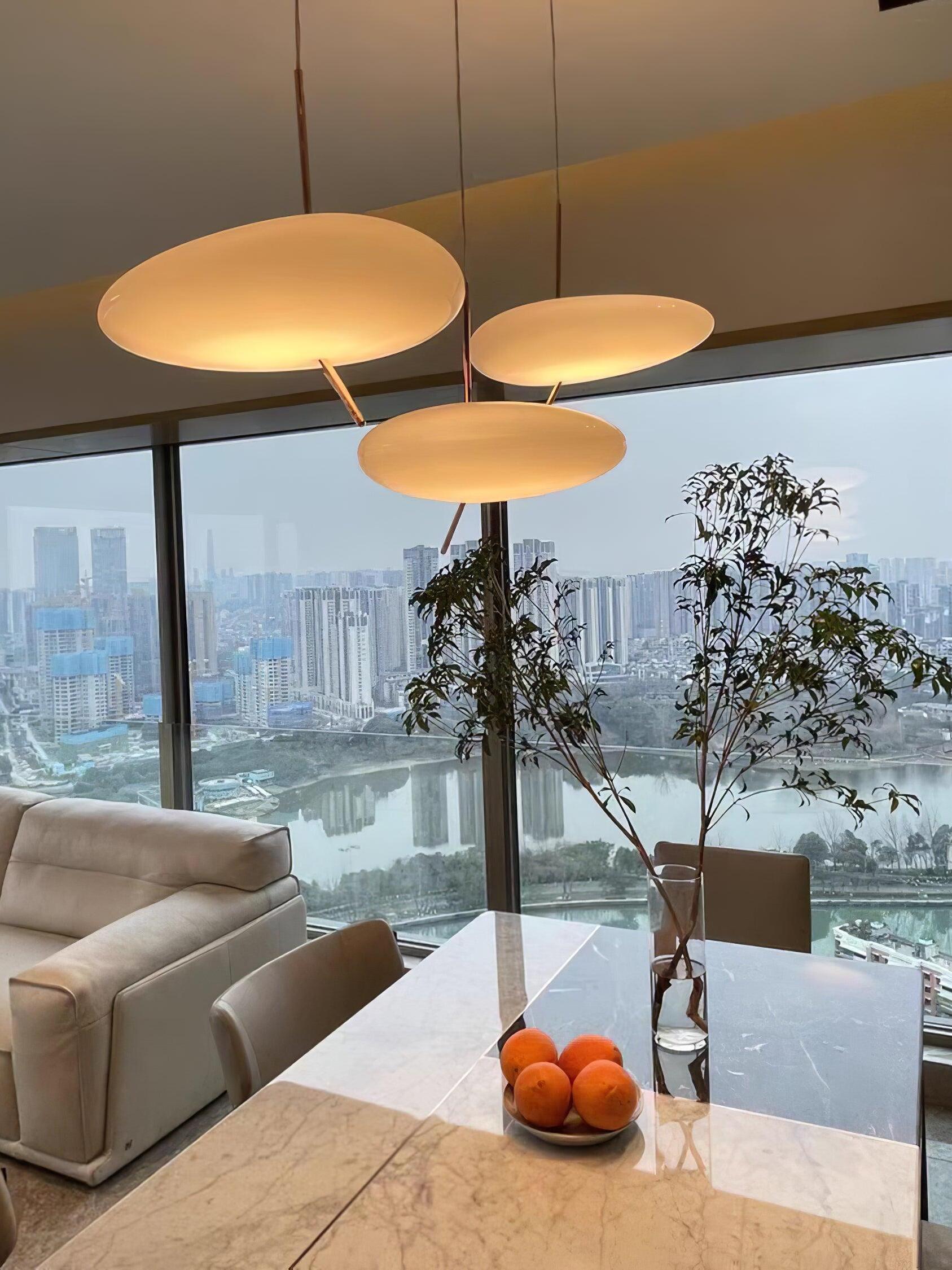 Warm-looking pendant shades above a table near large windows and a sofa