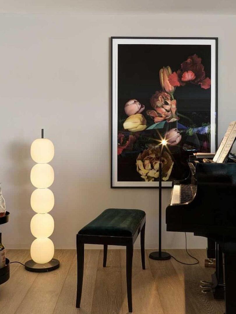 Five-globe lamp near a piano and flower artwork