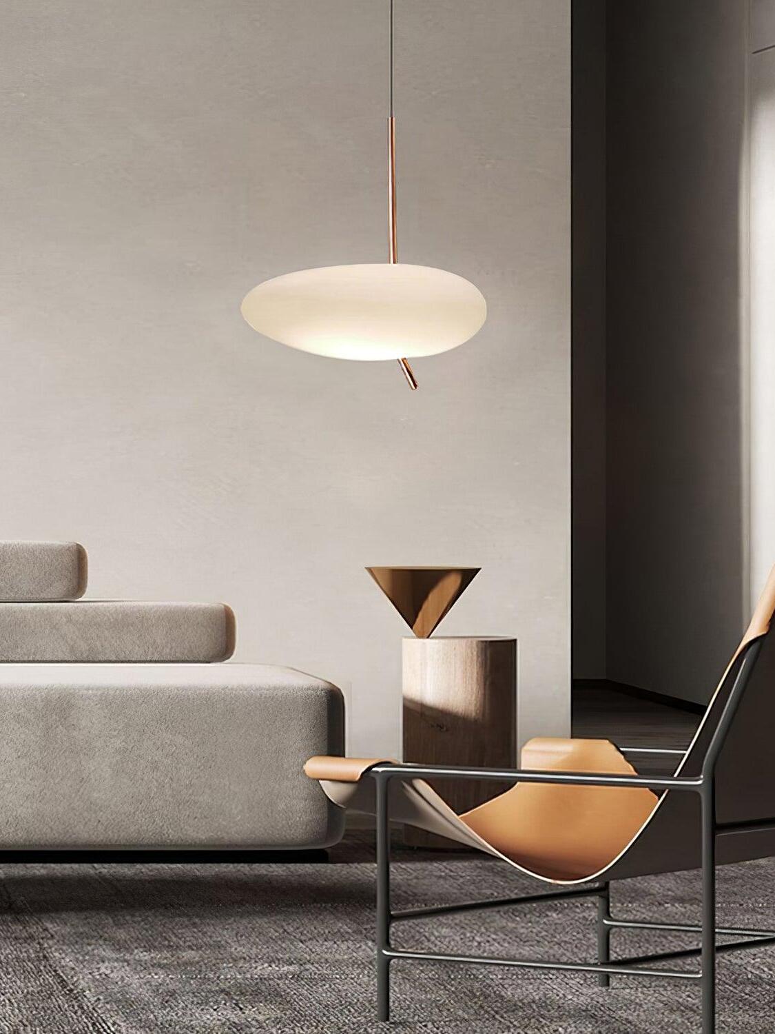 White pebble-shaped pendant beside a sofa, black lounge chair and triangular table lamp