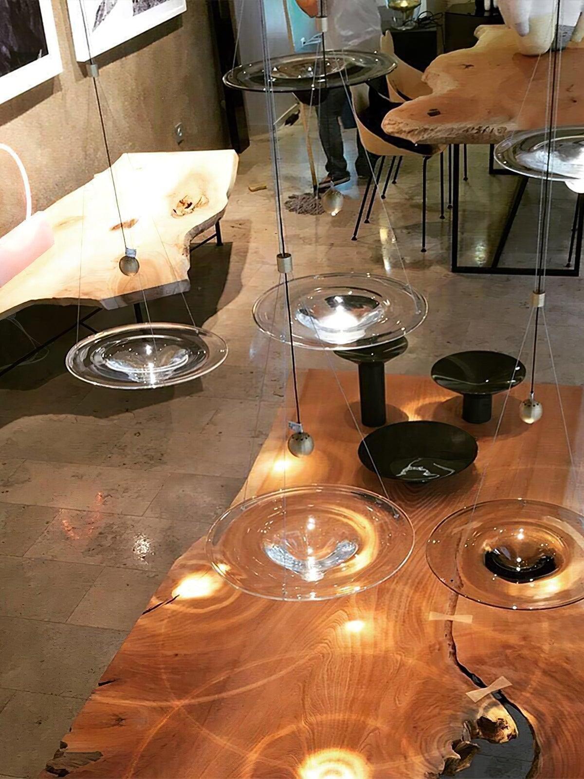 Clear disc pendants grouped above wooden table