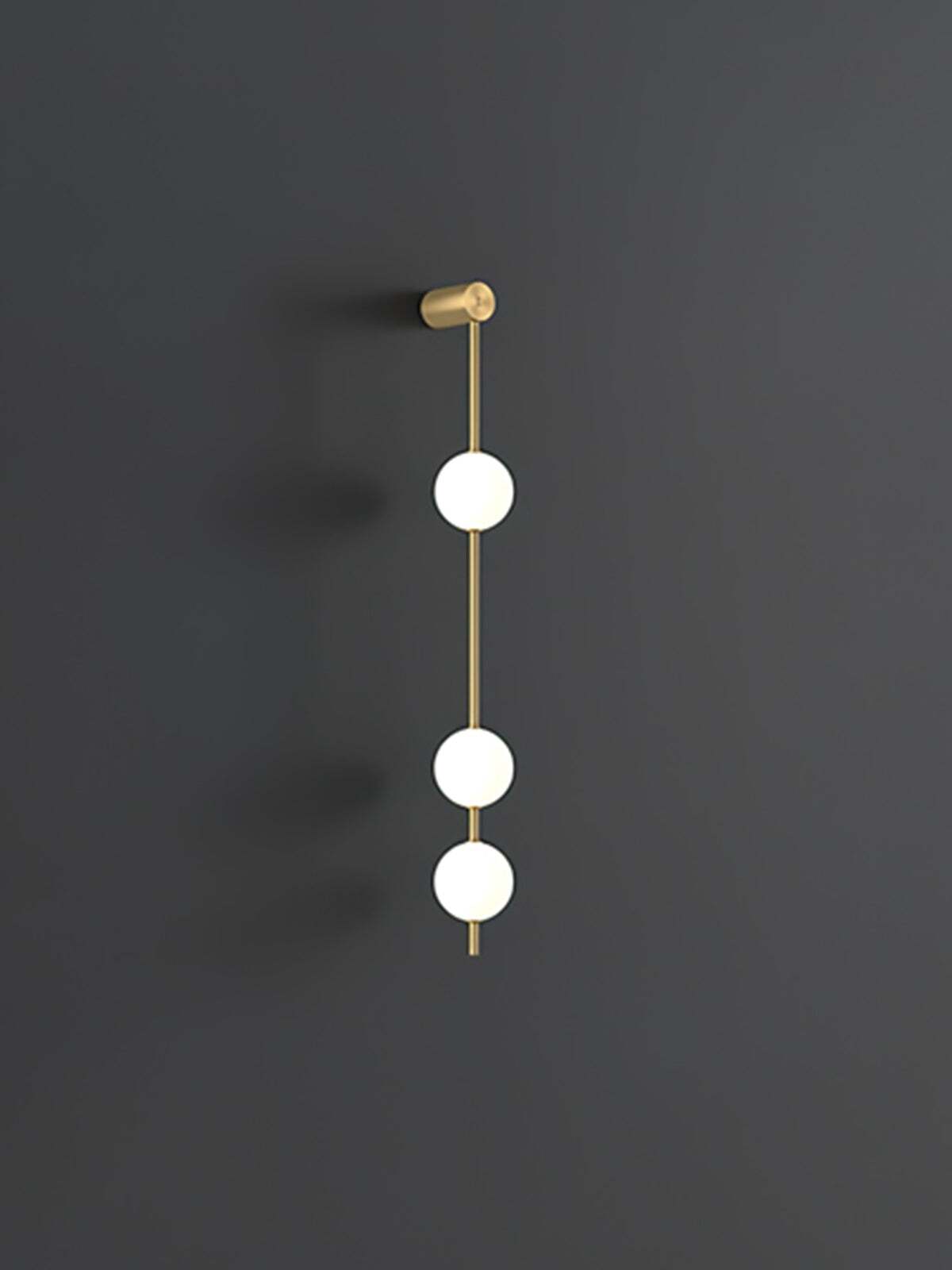 Enlarged three-globe wall lamp with lit white spheres and gold-colour rod against dark grey
