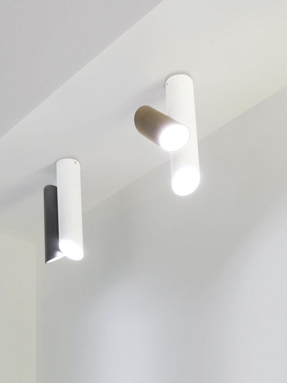 Two separate Tubes fixtures on a ceiling, one white and gold-tone and one white and black