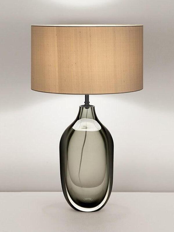 Smoky bottle-shaped lamp with textured beige shade on pale table