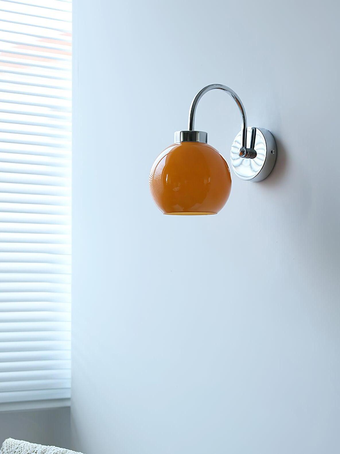 Unlit orange glass globe below curved arm on wall beside blinds