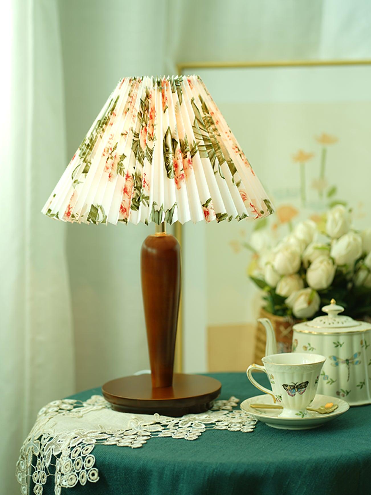 Brown lamp with floral pleated shade on dark covered table