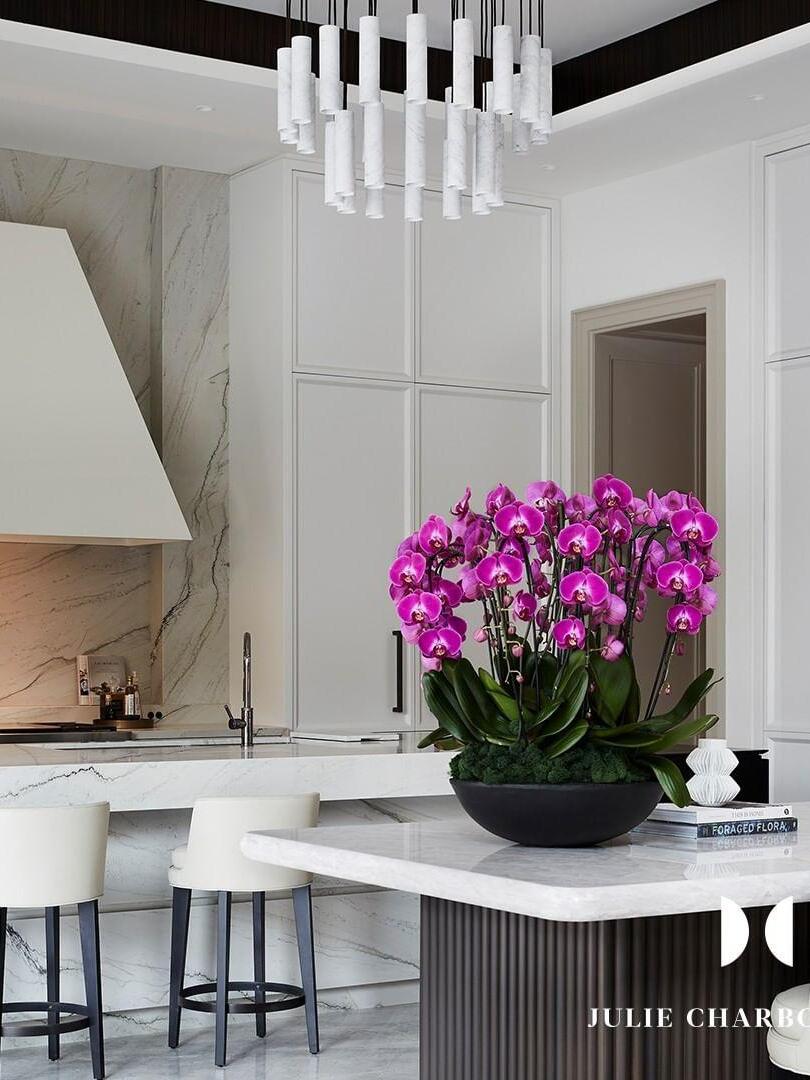 White Silo cylinder cluster above a kitchen counter with bright pink orchids and bar stools