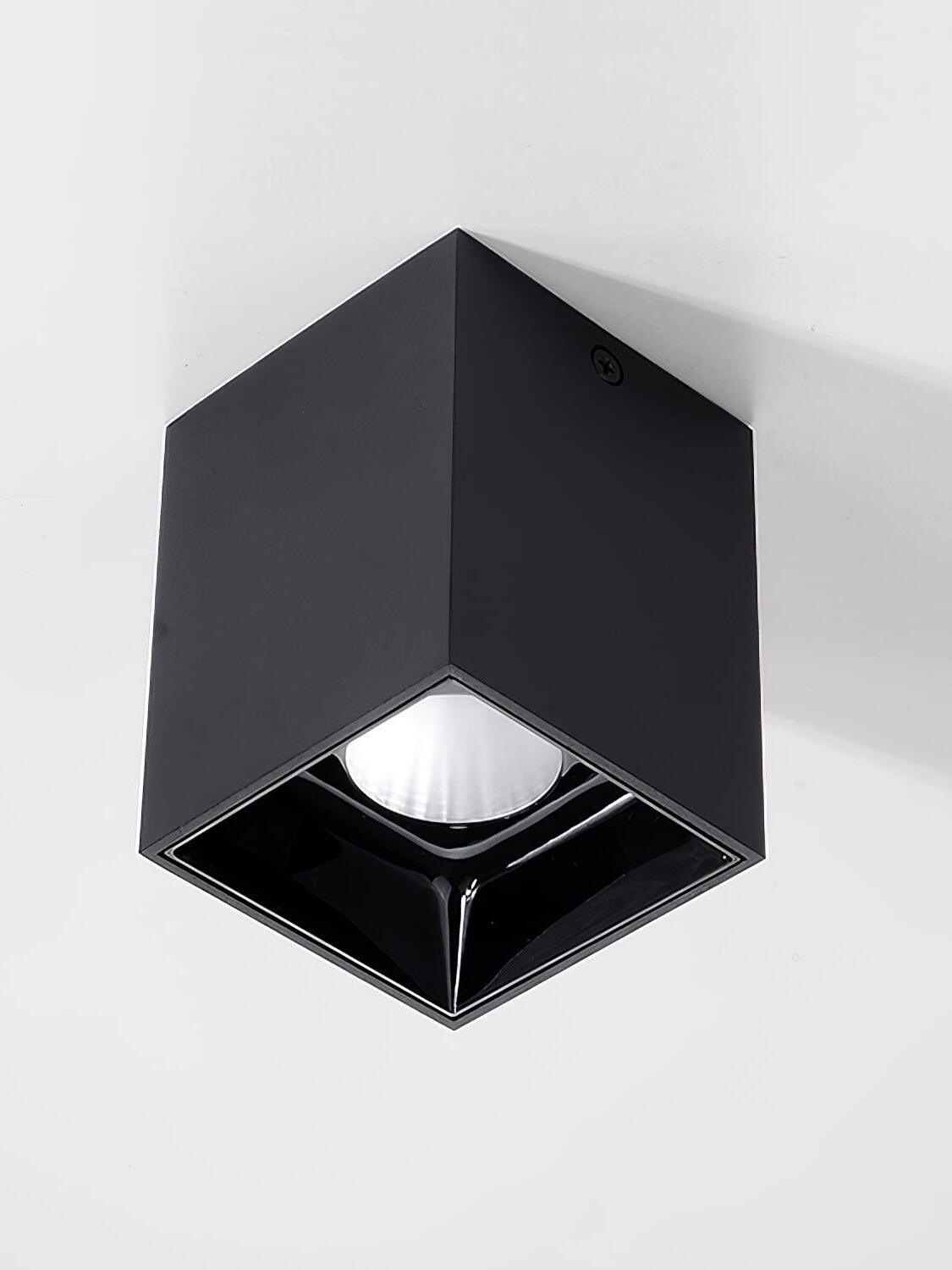 Low view of a black ceiling spotlight with a round reflector inside a glossy black square recess