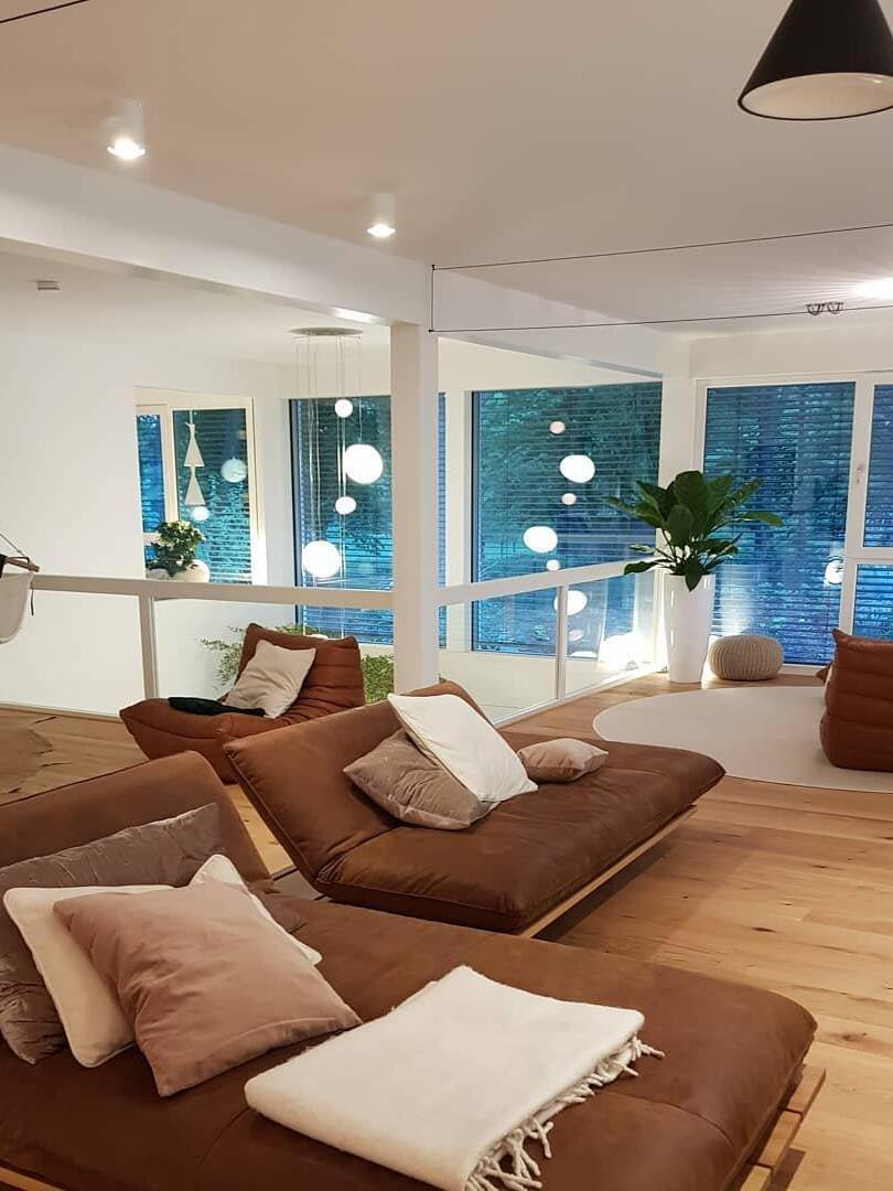Brown-sofa lounge with a partial black cone at upper right, ceiling lines and distant globe lights