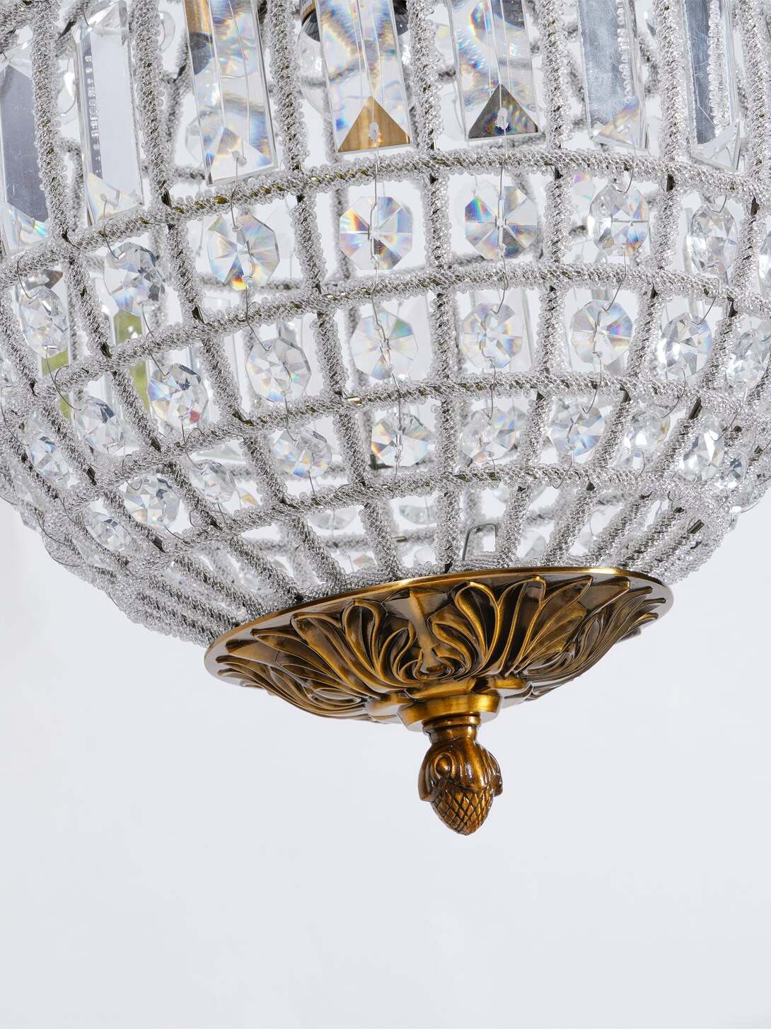 Lower globe detail with round crystals, rectangular pieces above and a carved gold-tone bowl and finial